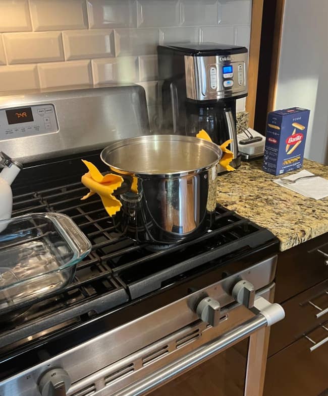 Pot of boiling h2o connected a stove with silicone pasta-shaped grips. Empty pasta container and java shaper connected antagonistic suggest cooking preparation