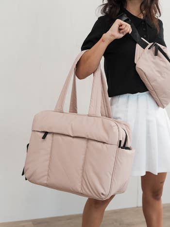 model holding a large beige shoulder bag suitable for shopping or travel