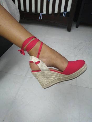Person wearing a reddish  wedge espadrille footwear  with ankle ties