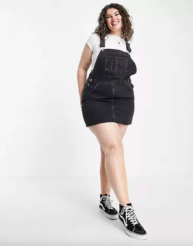 Model in a black denim overall with a skirt bottom 