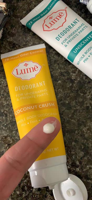 Finger applying a pea-sized magnitude  of coconut crush deodorant from a conduit  onto skin