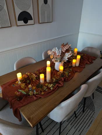 Dining array  acceptable   with candles, a fall-themed runner, and a floral centerpiece, creating a cozy, elegant atmosphere