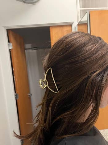 Person side view with a gold hair claw clip in their hair