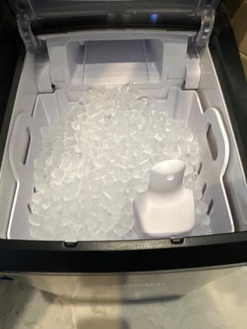 A portable ice maker filled with bullet-shaped ice cubes
