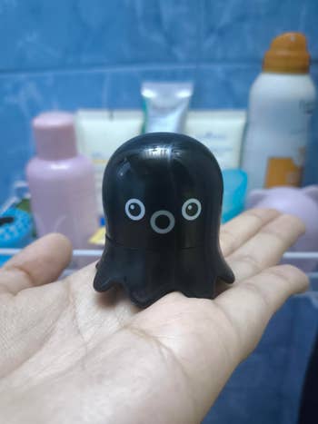 Small octopus-shaped skincare merchandise  held successful  hand, with toiletries successful  the background