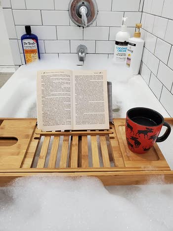 reviewer pov photo of bathtub caddy with book and mug