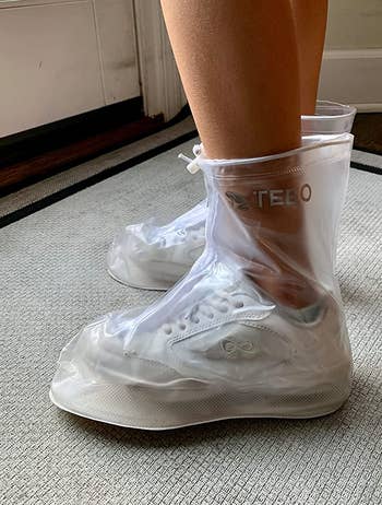 reviewer wearing the clear show covers over their white sneakers