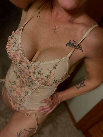 Person wearing a floral lace bodysuit with tattoos disposable   connected  arms and shoulders