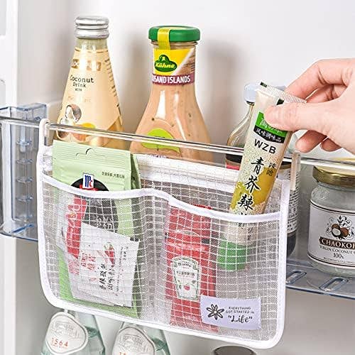 Hand inserting a packet into a mesh refrigerator storage organizer filled with various condiments