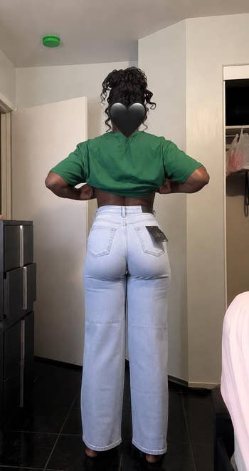 Person successful a cropped apical and high-waisted jeans displays the acceptable of the jeans successful a country setting