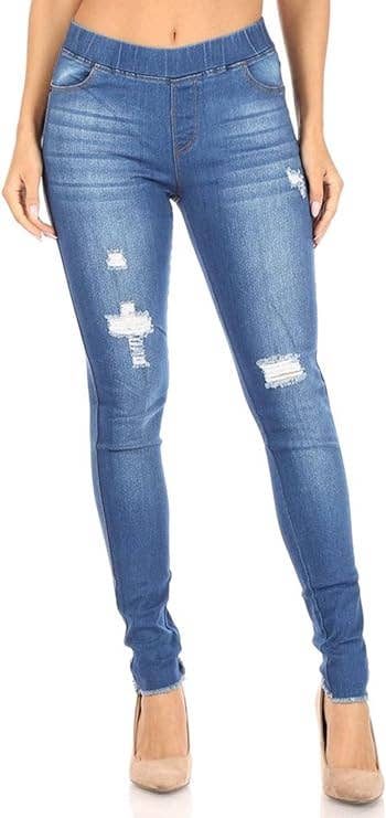A person wearing blue distressed skinny jeans with an elastic waistband