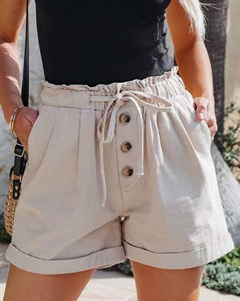 a model wearing the shorts in beige paired with a black top