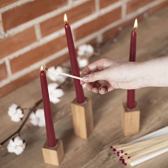 a dark maroon taper candle being lit