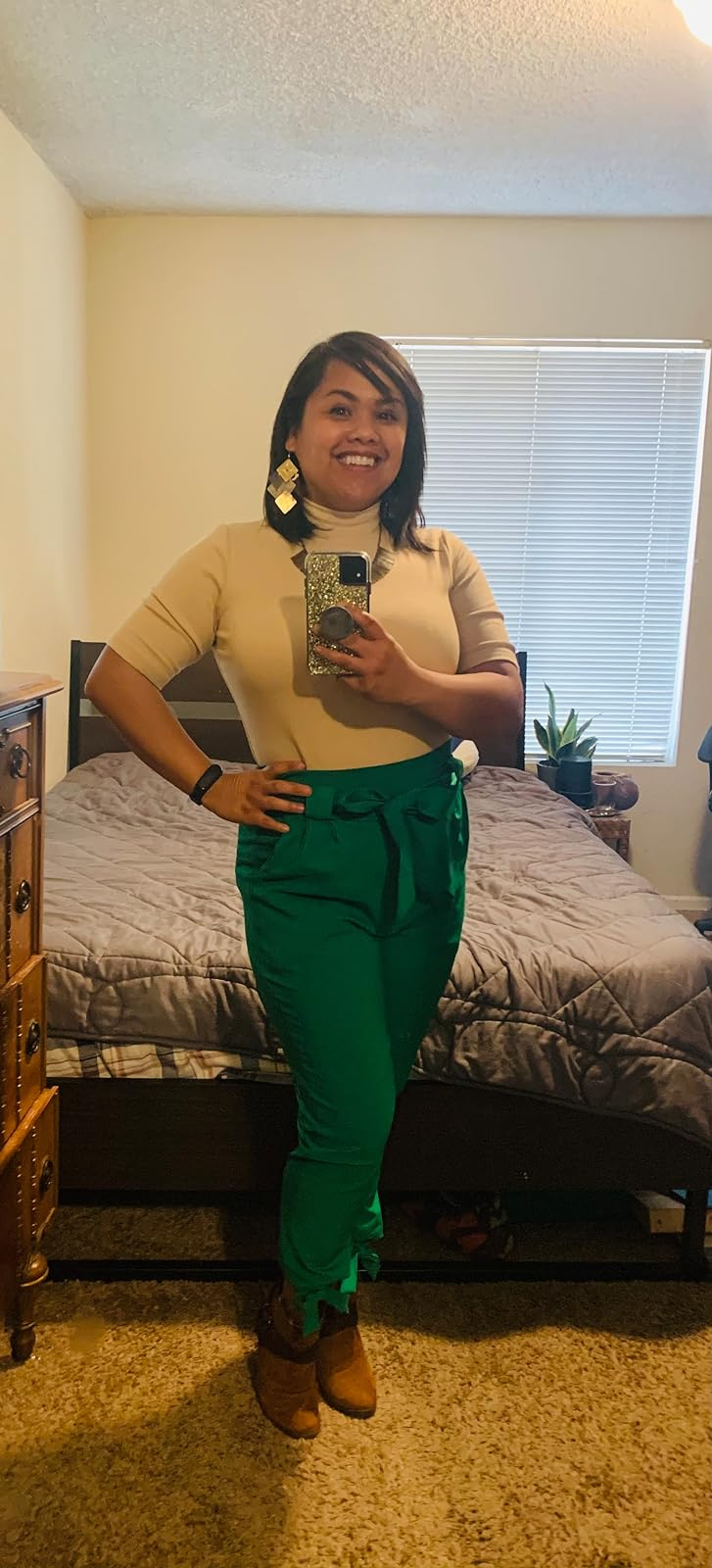 Reviewer wearing a beige top, green high-waisted pants, and brown boots