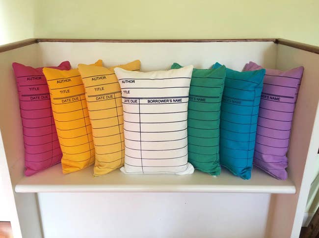 Library card-themed pillows lined up connected a shelf, each with substance fields for author, title, and borrower details