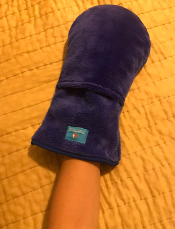 Reviewer with their hand in an oversized blue mitten 
