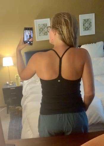 Reviewer showing the black top with a slightly open back and a Y-shaped spaghetti strap 
