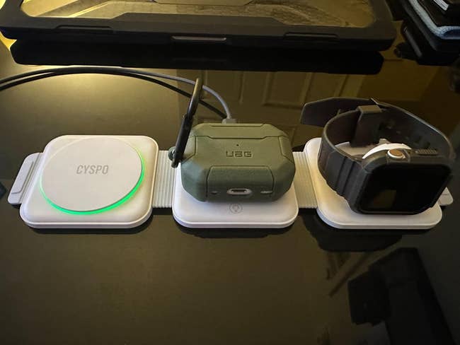 Three wireless charging pads with devices on them including earbuds, a smartwatch, and a phone