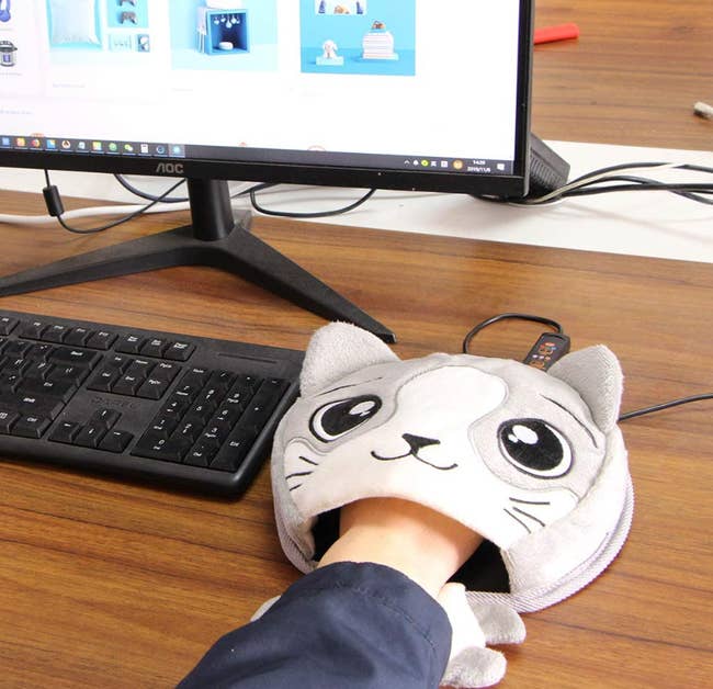 person using cat-themed handwarming mousepad at computer
