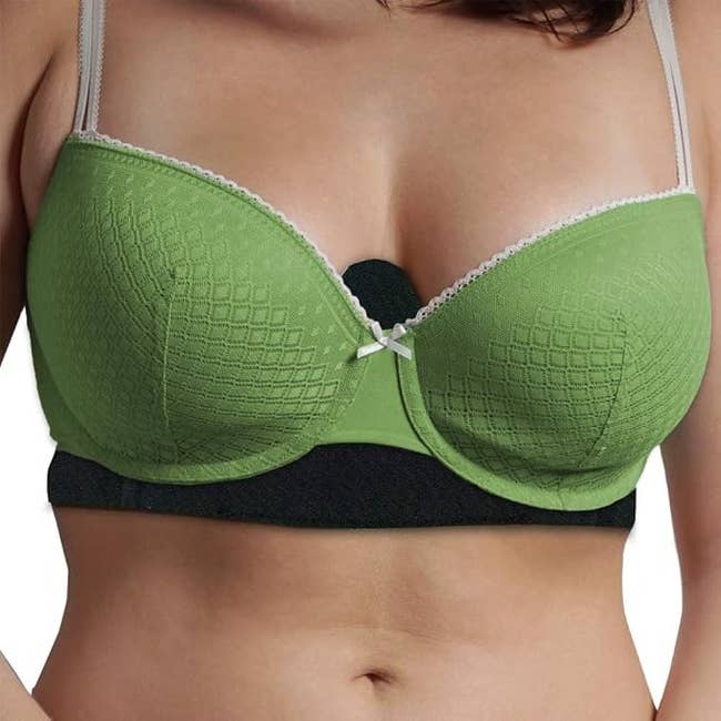 A person wearing a textured bra with underwire, featuring a small bow at the center and lace trim on the edges