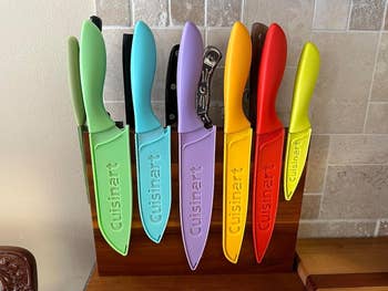 A set of six Cuisinart knives with matching blade guards, displayed in a wooden block on a kitchen counter