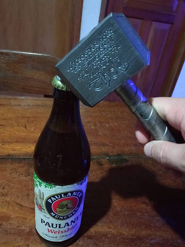 reviewer opening a beer with a bottle opener shaped as Thor's hammer