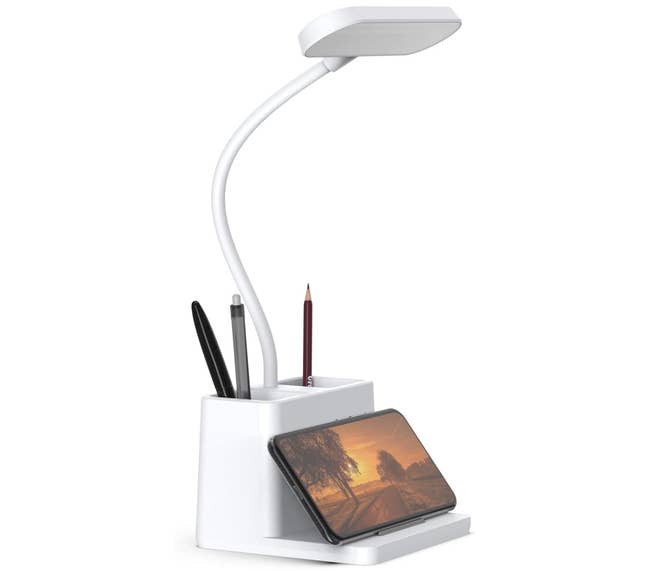 The desk lamp holding pens and a phone