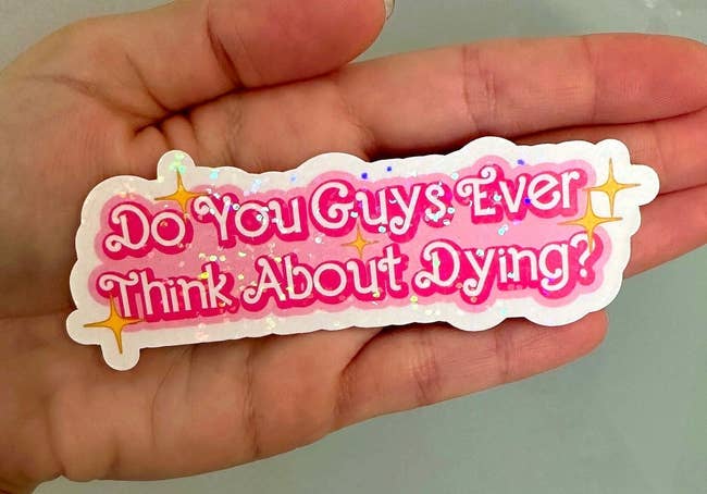 palm-sized sticker in curly pink font with sparkles that says 
