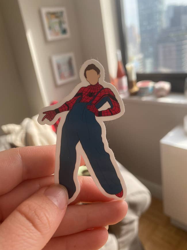 A sticker of Harry Styles doing the Fine Line pose while dressed as Spider-Man