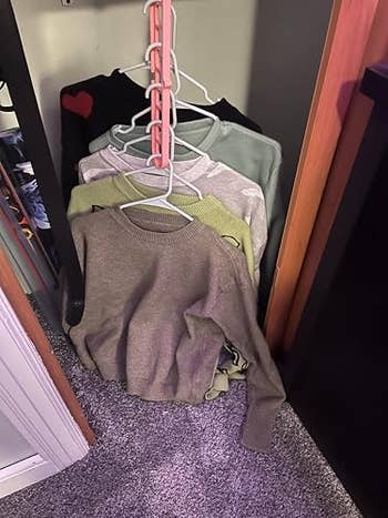 Sweaters neatly organized connected multi-tier hangers wrong a wardrobe, showcasing a space-saving retention solution