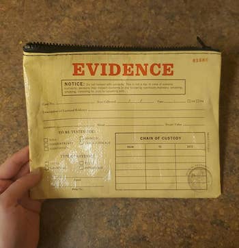 Hand holding a pouch designed to look like an evidence bag, with various fields and a 