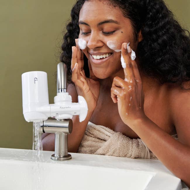 a model washing their face using the Filterbaby filter on their sink 