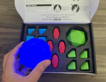 Person holding a luminous bluish  geometric crippled  portion   successful  beforehand   of box