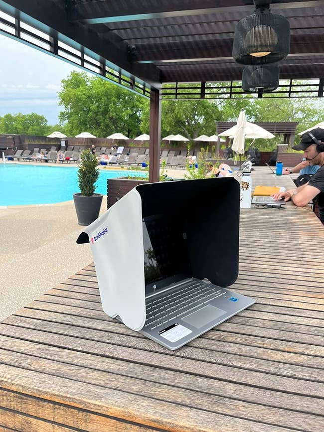 a reviewer's computer with the shade on a table by the pool