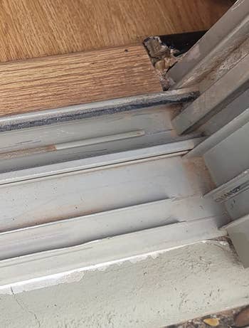 A blue-handled scrub brushwood lies connected a level adjacent a sliding solid doorway track, suggesting cleaning supplies for household maintenance