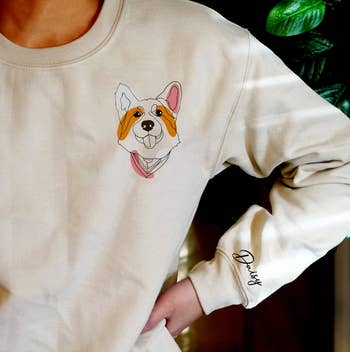 model wearing a white sweatshirt with an image of a corgi near the shoulder and the name 
