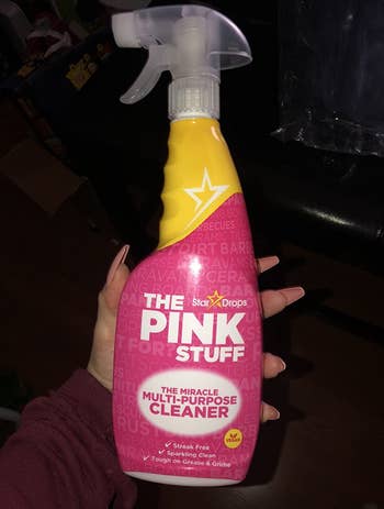 Reviewer holding The Pink Stuff spray cleaner