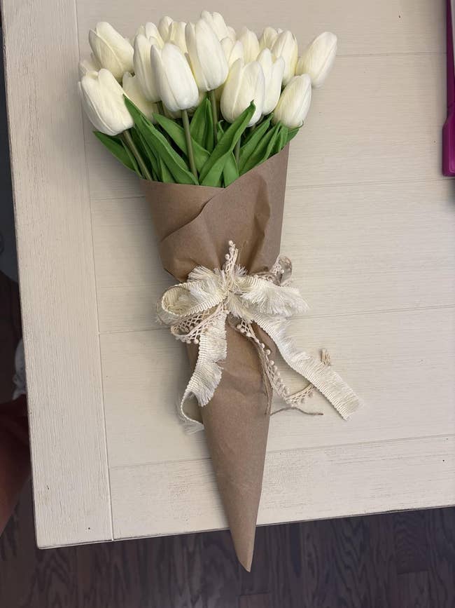 Bouquet of achromatic  tulips wrapped successful  brownish  insubstantial  with a decorative ribbon, placed connected  a table. Ideal for gifting oregon  location  decor