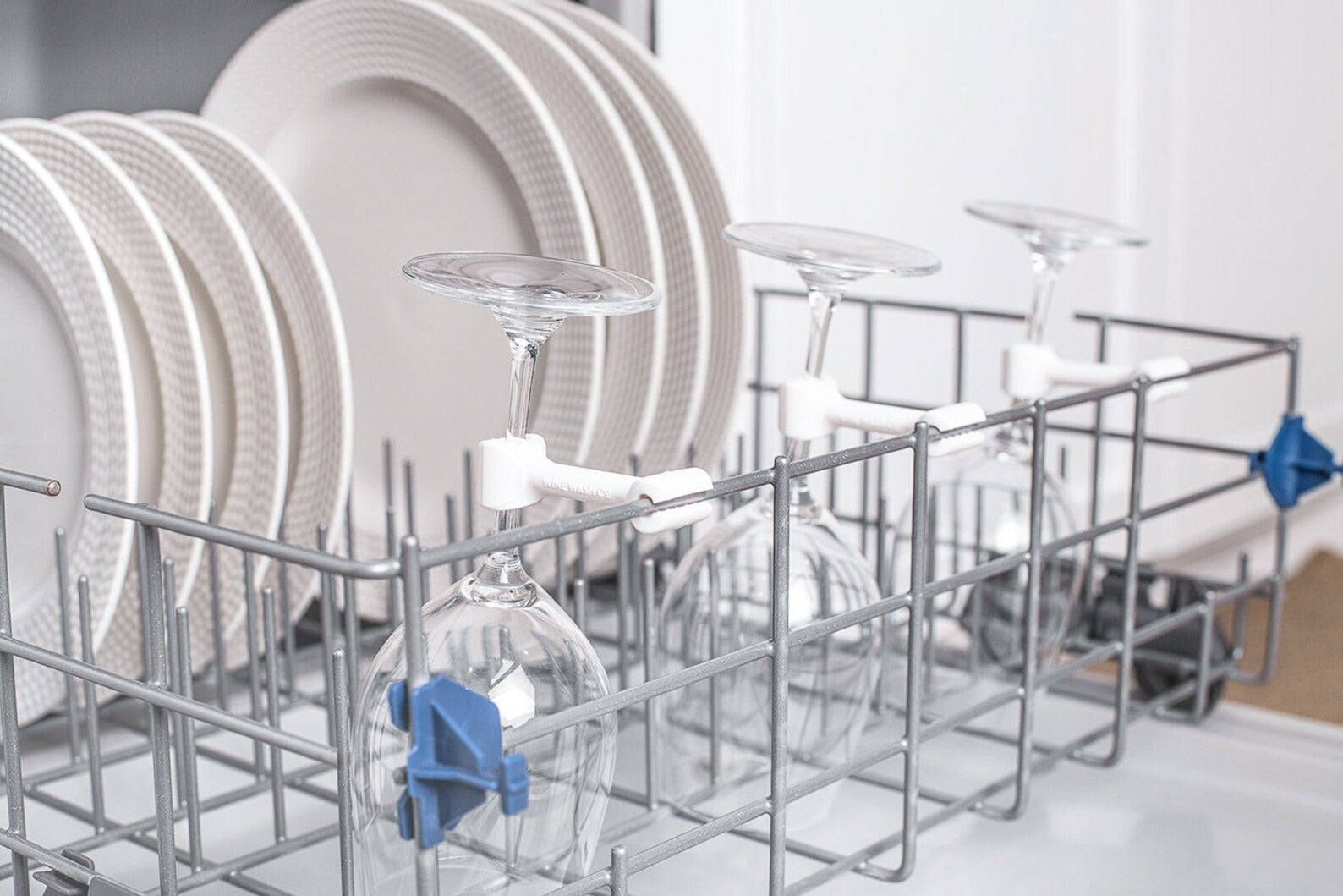 white clips attaching wine glasses to the edge of a dishwasher basket