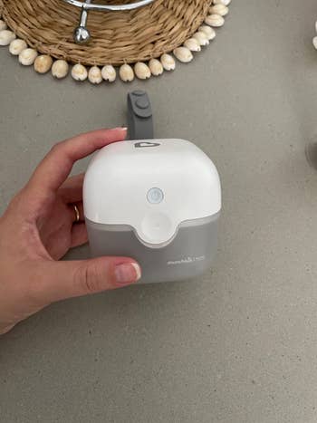 reviewer hand holding the box-shaped sterilizer