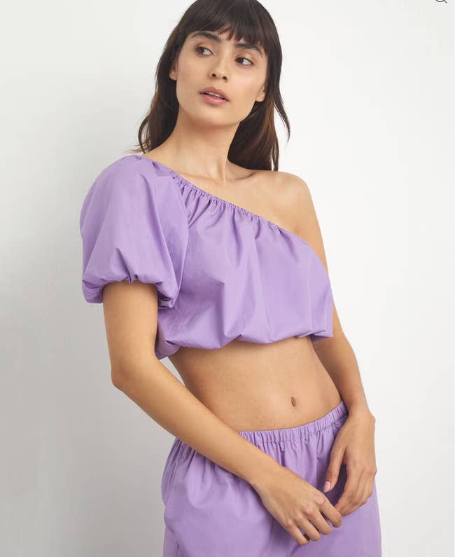Model in a lavender ruched poplin one-shoulder top with a bubble sleeve 