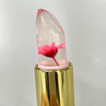 Clear lipstick with a tiny  pinkish  angiosperm  inside, encased successful  a golden  tube