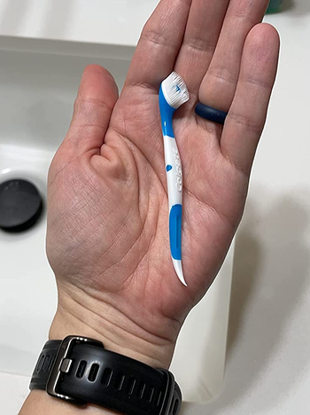 Reviewer holding one of the disposable toothbrushes in their hand