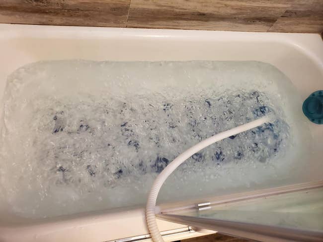 reviewer's tub with the mat on the bottom of the tub and many bubbles