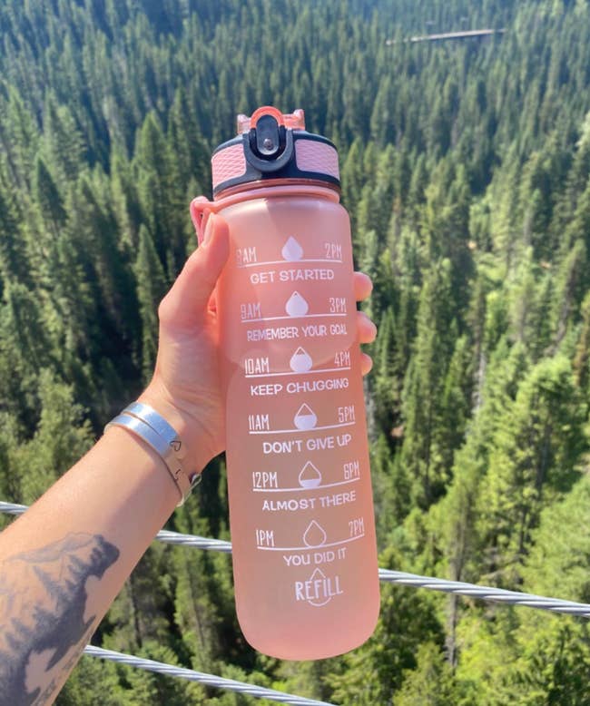 A reviewer holding up a pink time marked water bottle