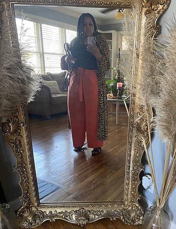 Different reviewer wearing orange belted wide leg pants while looking in the mirror