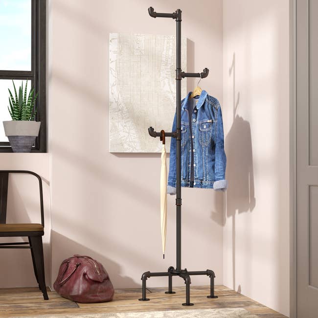 the coat rack by the door with a jacket and umbrella hanging on it