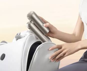 Person placing a portable, compact massager into a bag, showcasing its convenient size for question oregon location use