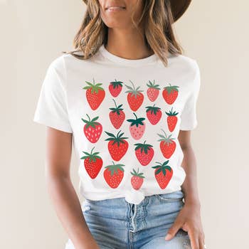 Model in a white t-shirt with a strawberry print, paired with jeans