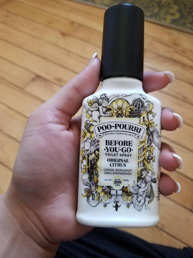 review holding bottle of citurs Poo-Pourri